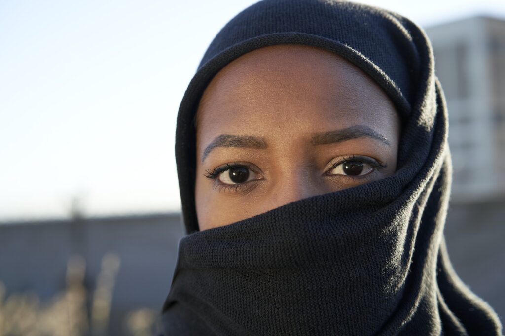 Close-up of face of a young Muslim girl with hijab looking at the camera.